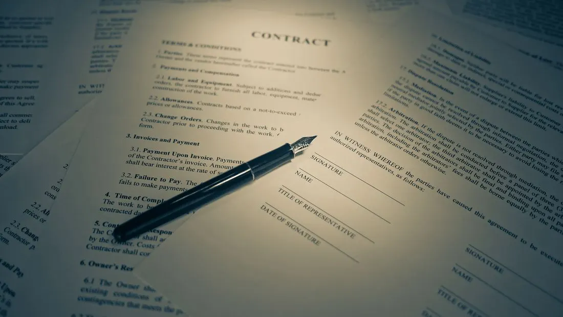 A black fountain pen lying on a printed contract, beside blank signature, name and date lines.