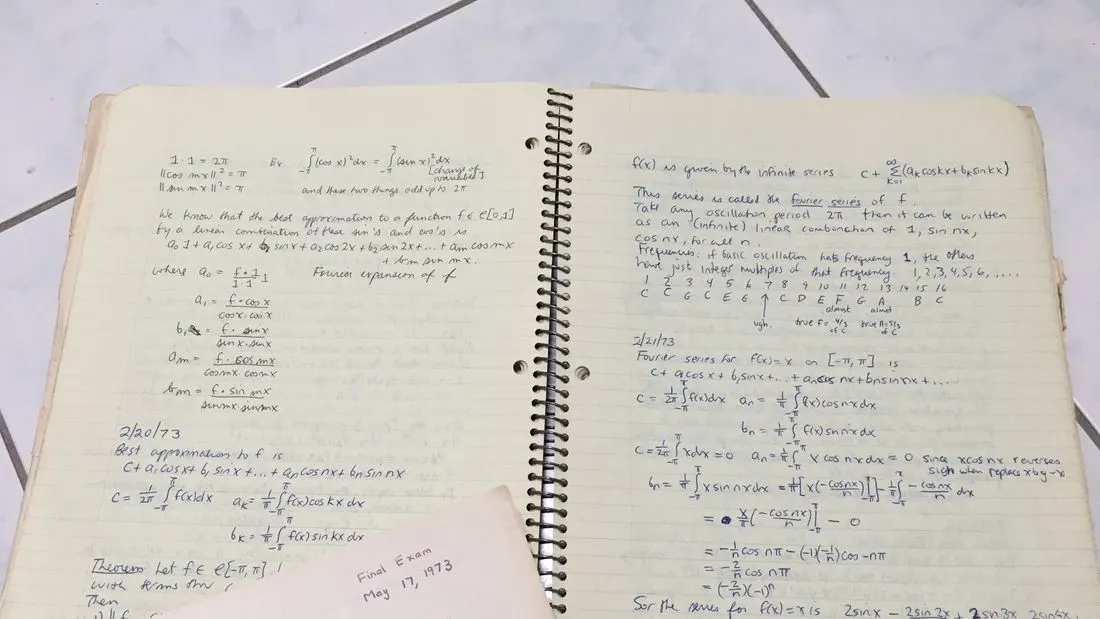 Two open pages of a spiral notebook covered in handwritten calculus notes on Fourier series, with an envelope marked Final Exam May 17, 1973 in the corner.
