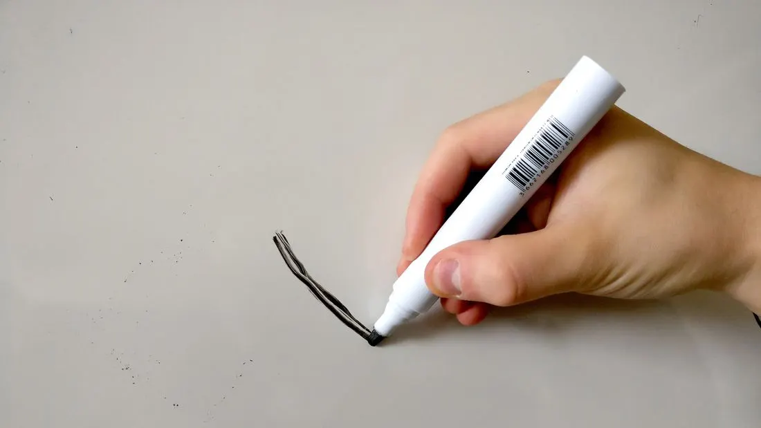 A hand holding a white marker and starting to draw a line on a plain white whiteboard.